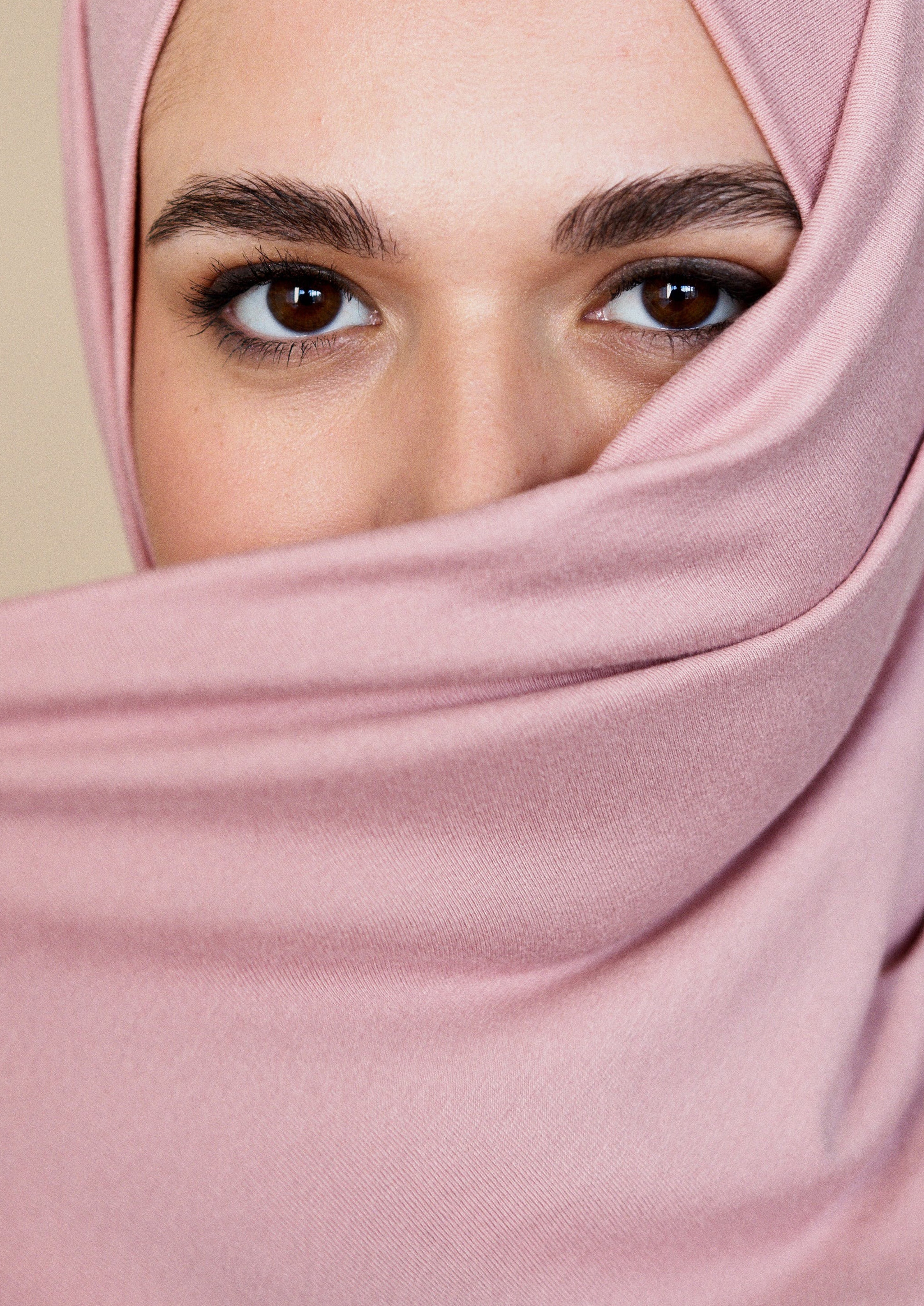 Frau, deren Gesicht halb von einem rosa Hijab verdeckt ist