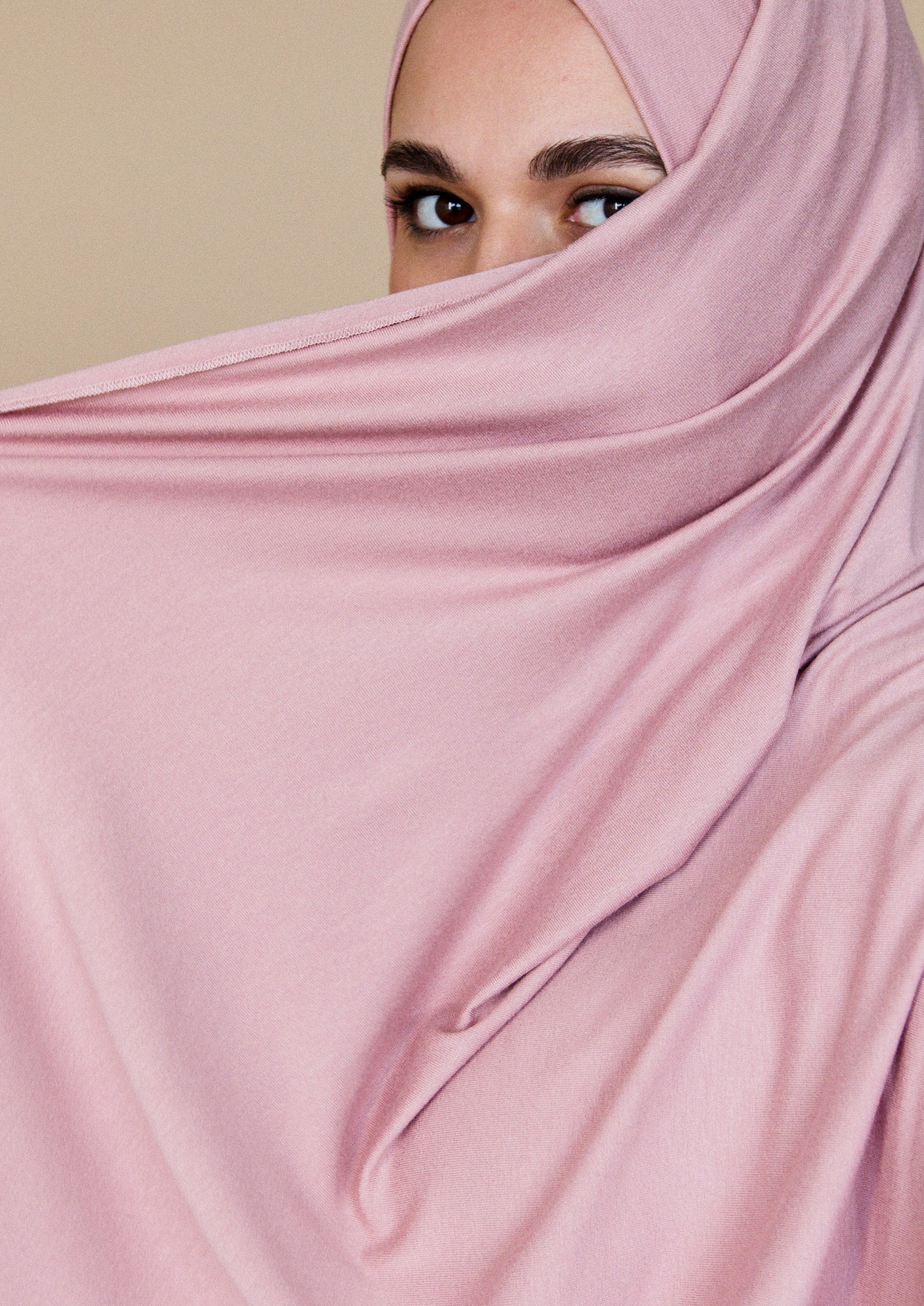 Frau, deren Gesicht bis auf die Augen von einem rosa Hijab verdeckt ist