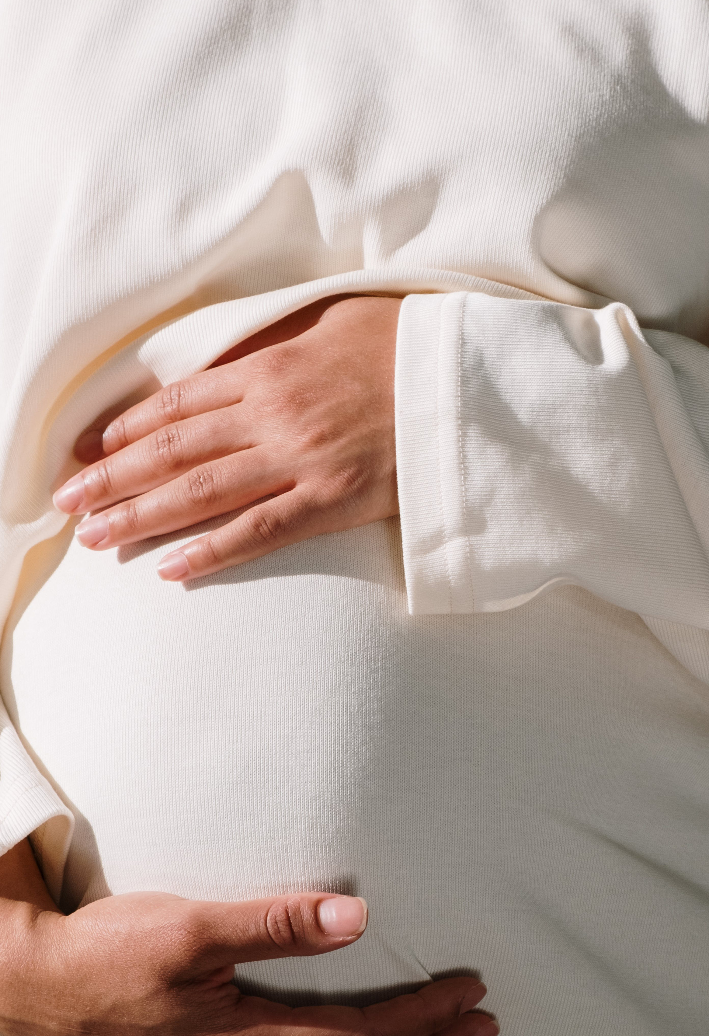 Bauch einer schwangeren Frau mit ihren Händen darauf